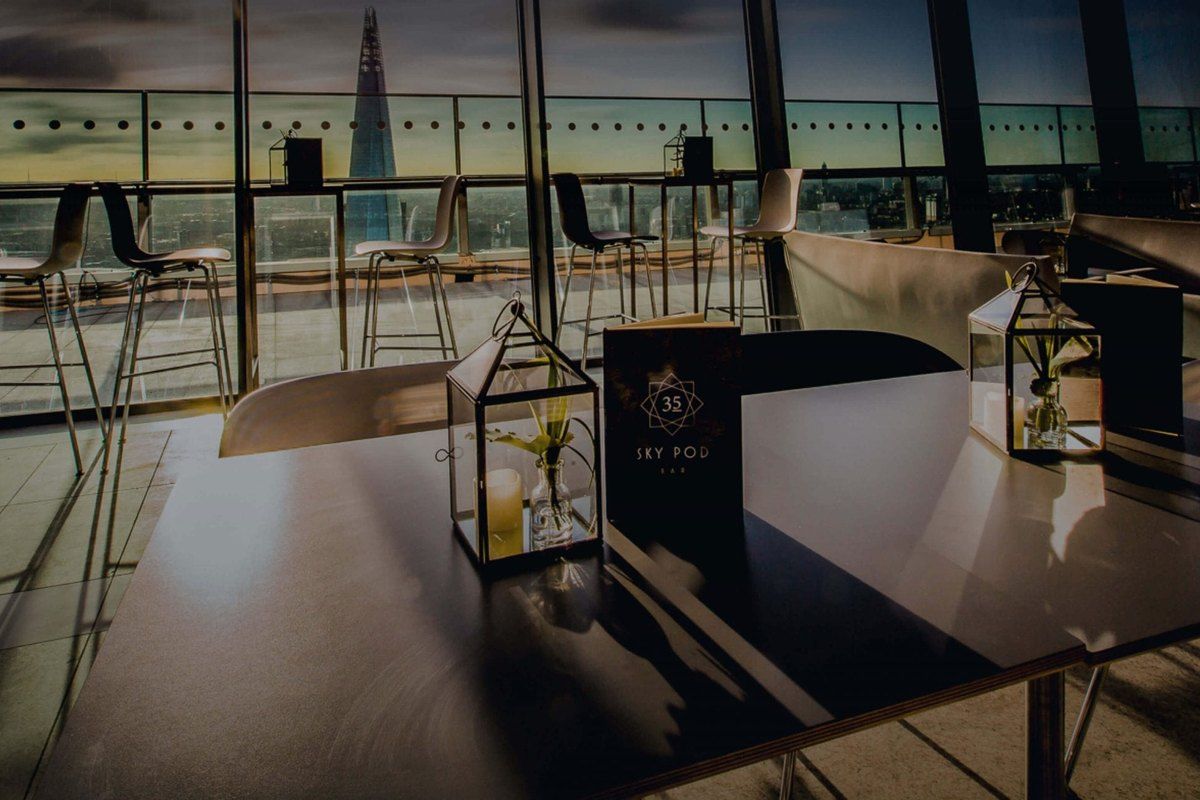 Tables at the Sky Pod bar in Sky Garden with the Shard on the skyline at dusk