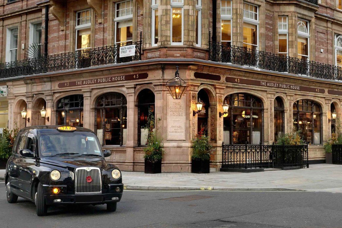 The Victorian corner façade of The Audley Public House on Mount Street, Mayfair, with a black cab outside