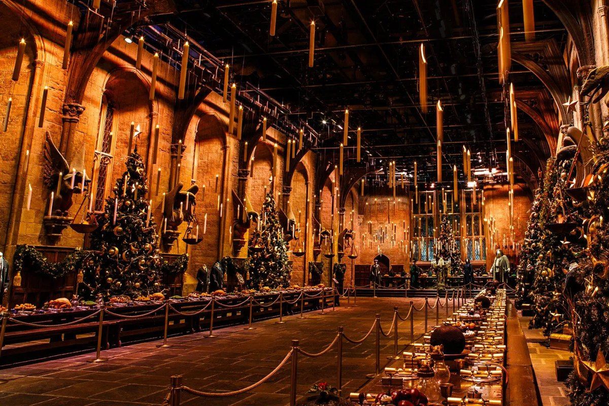 The Great Hall set dressed for Christmas with trees, a feast and floating candles during Hogwarts in the Snow