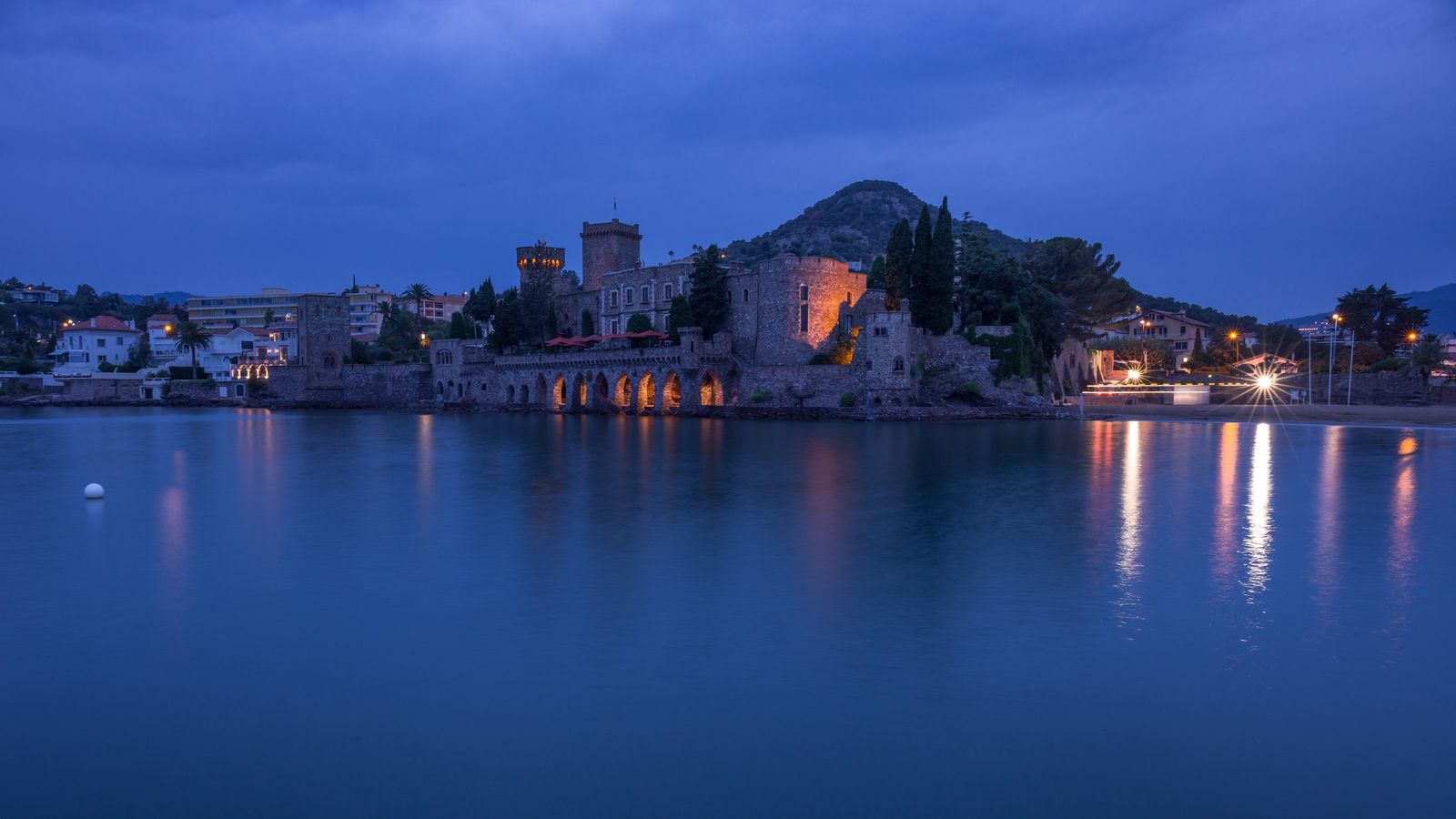 The Château de la Napoule lit up across the water in the evening