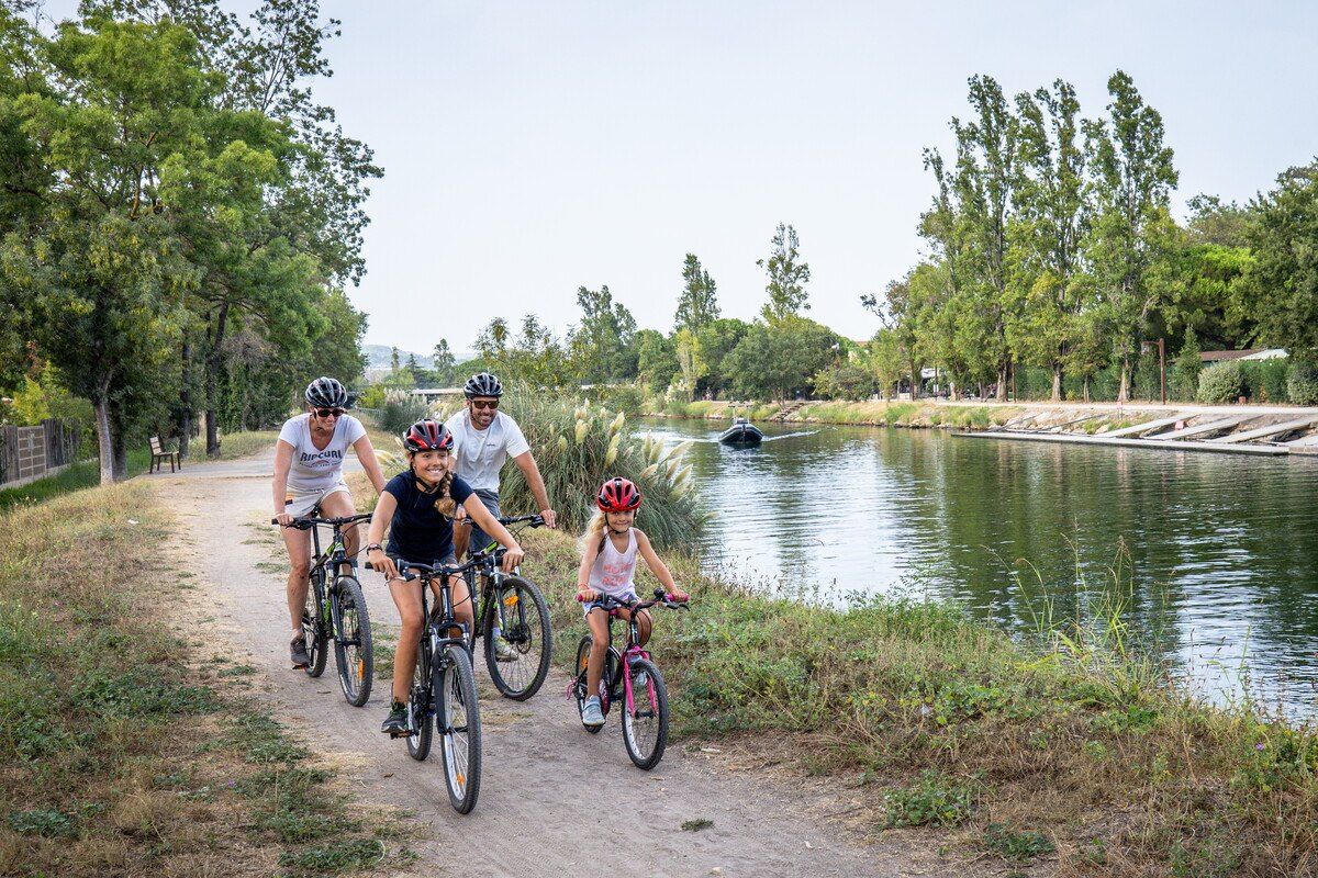 A family on bikes on the riverside path of the Siagne in Mandelieu, the water still beside them
