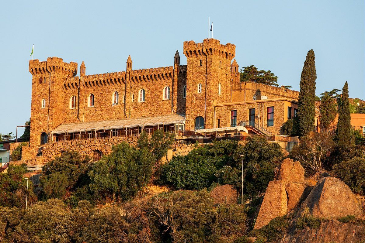 The red porphyry Château d'Agecroft on the rocks above the sea at La Rague