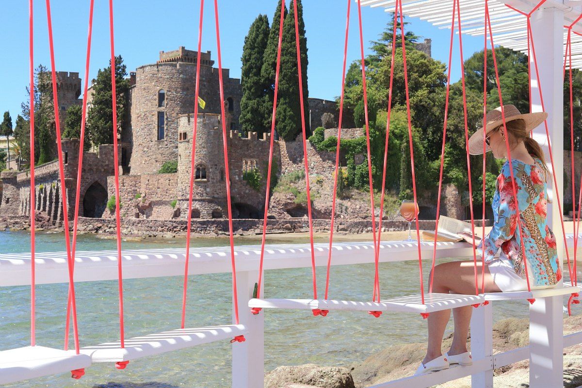 The rope-and-plank deck of Dolce Farniente in the port of La Napoule, with the château across the water