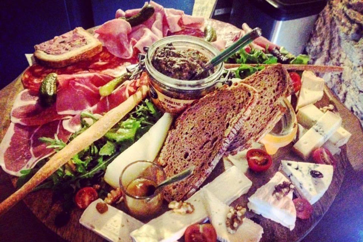 A board of charcuterie, cheese and bread with a glass of wine at La Petite Source, La Napoule