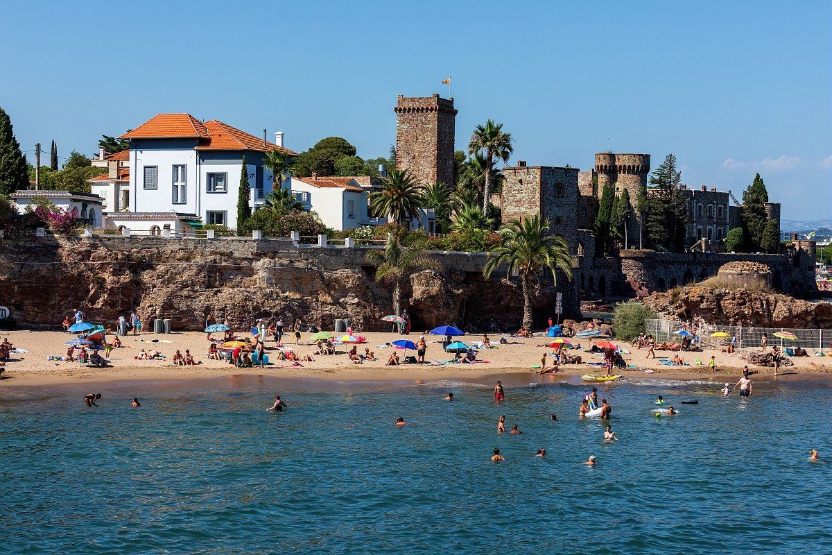 Families on the small sandy beach below the Château de La Napoule, in shallow clear water