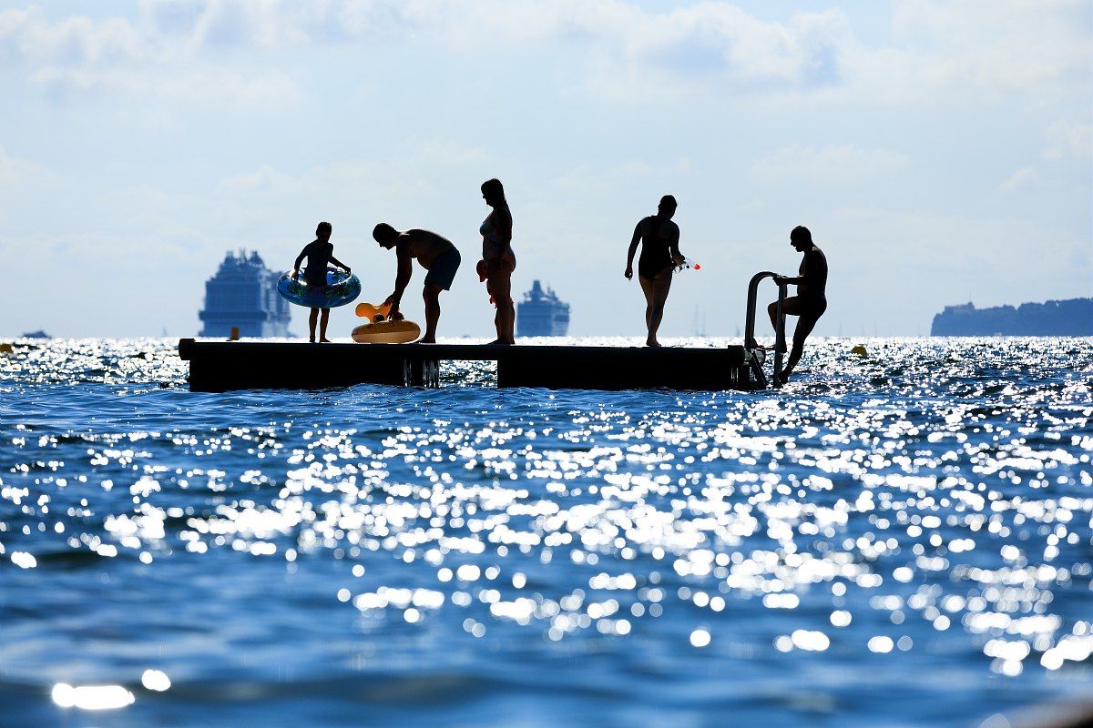 Children jumping from a bathing pontoon in the sparkling sea off Mandelieu's Robinson beach