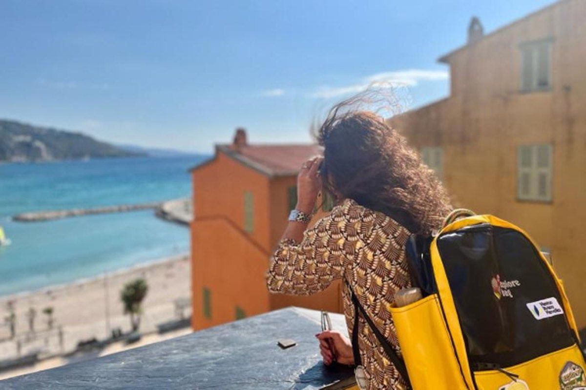 An explorer with the yellow My Explore Bag backpack looking out over Menton's beach from the Rampes Saint-Michel
