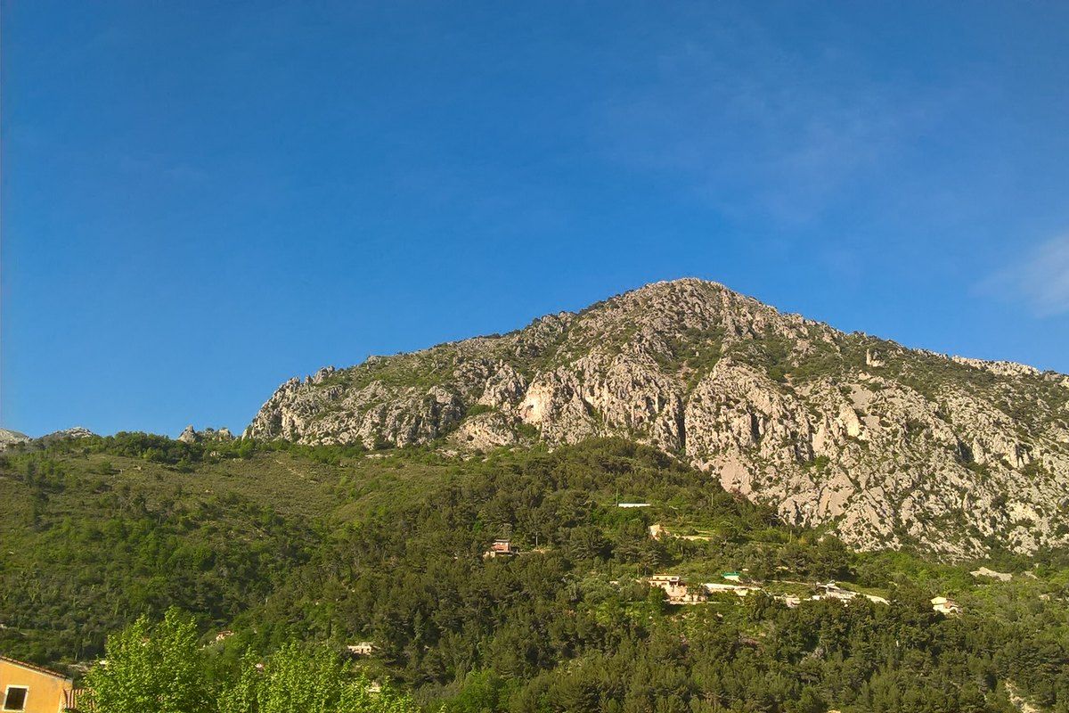 The limestone crest of the Roc d'Orméa above wooded slopes, seen from Castellar