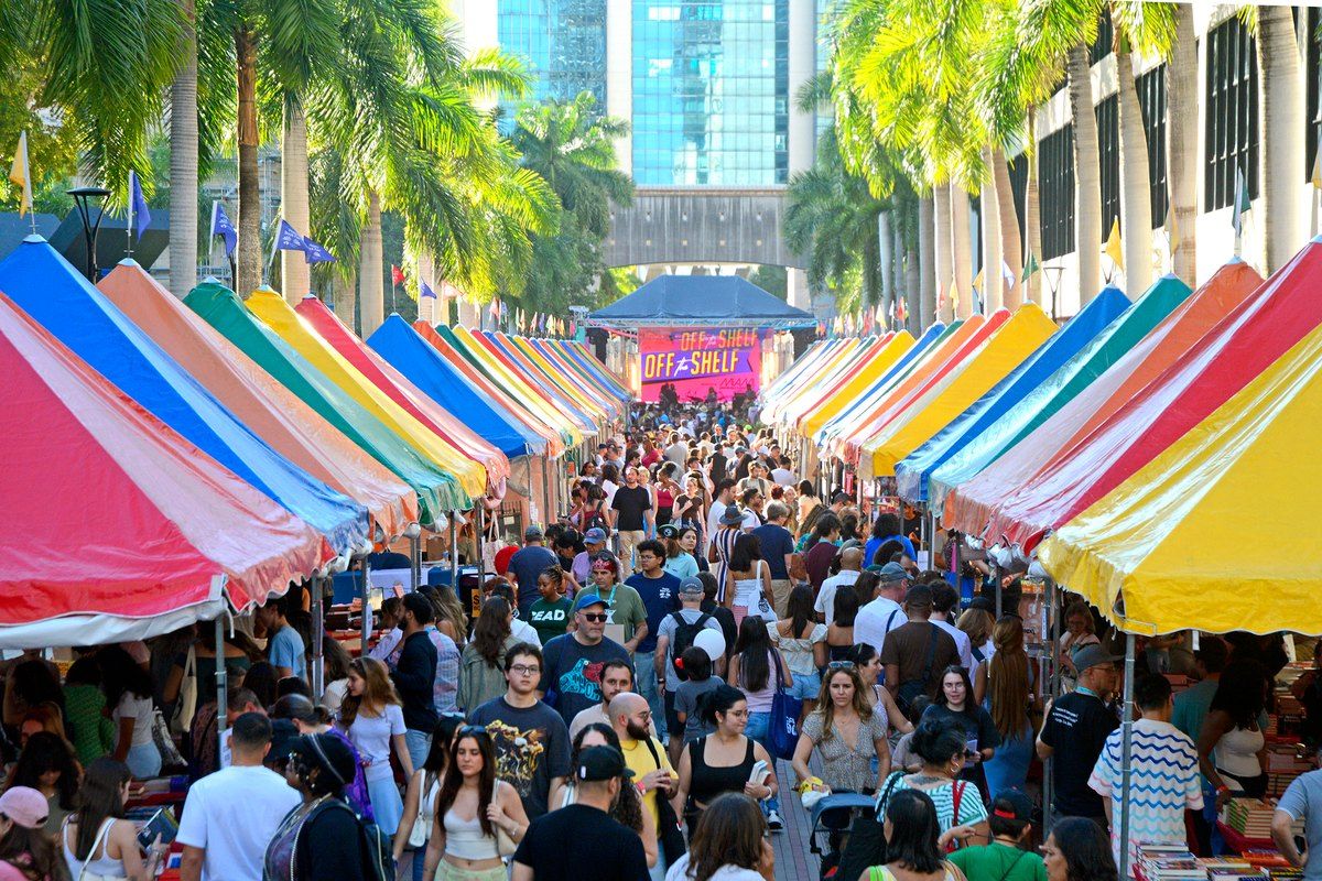 Crowds walking between rows of colourful tents at the Miami Book Fair street fair, Downtown Miami