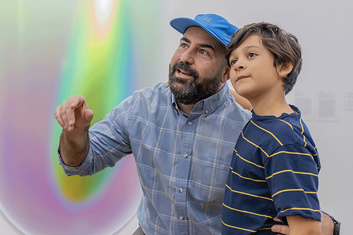A father and son looking up at a work of art in the galleries of Pérez Art Museum Miami