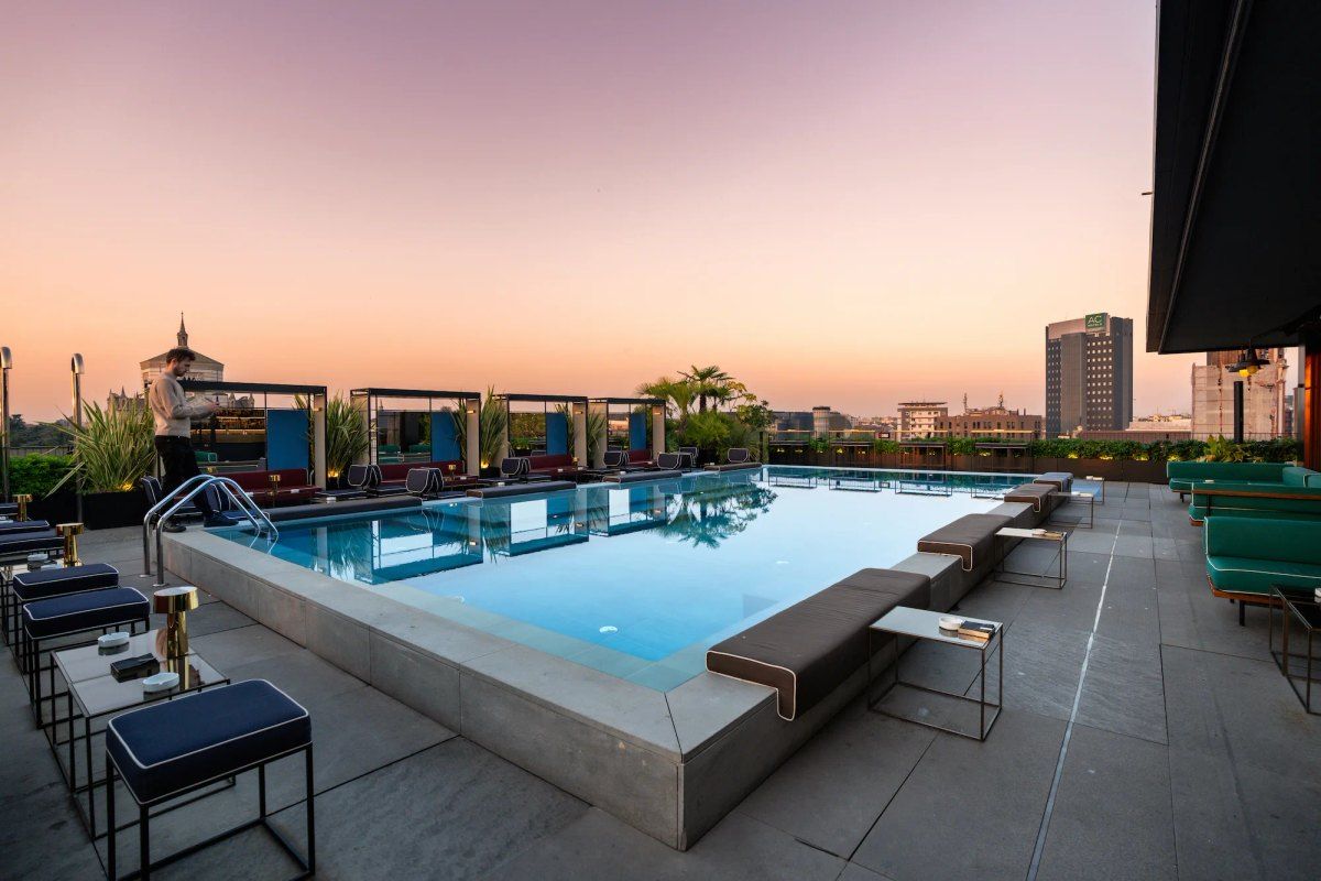 The rooftop pool and loungers of Ceresio 7 at dusk above Milan