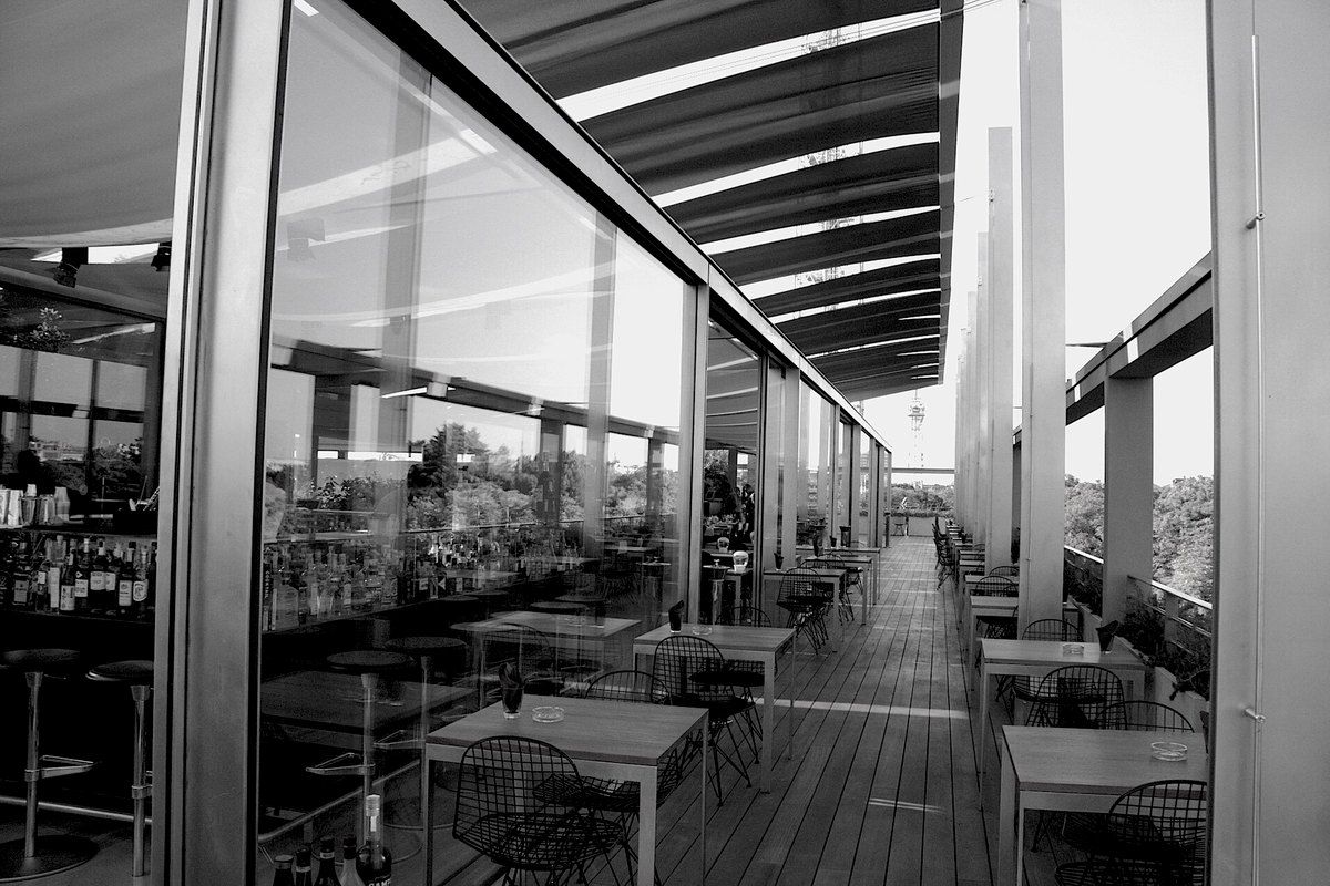 The glazed rooftop restaurant terrace of the Triennale Milano, in black and white