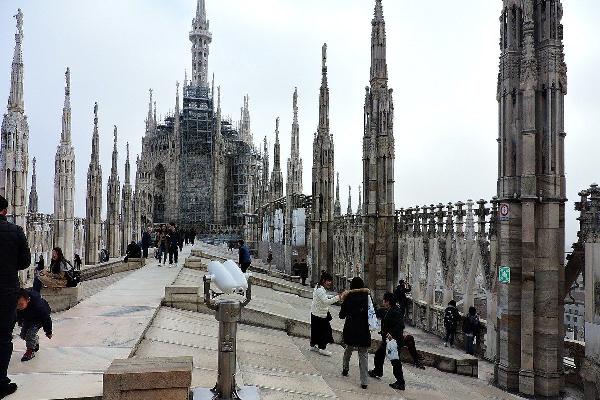 Visitors walking on the marble rooftop terraces of Milan Cathedral among its spires