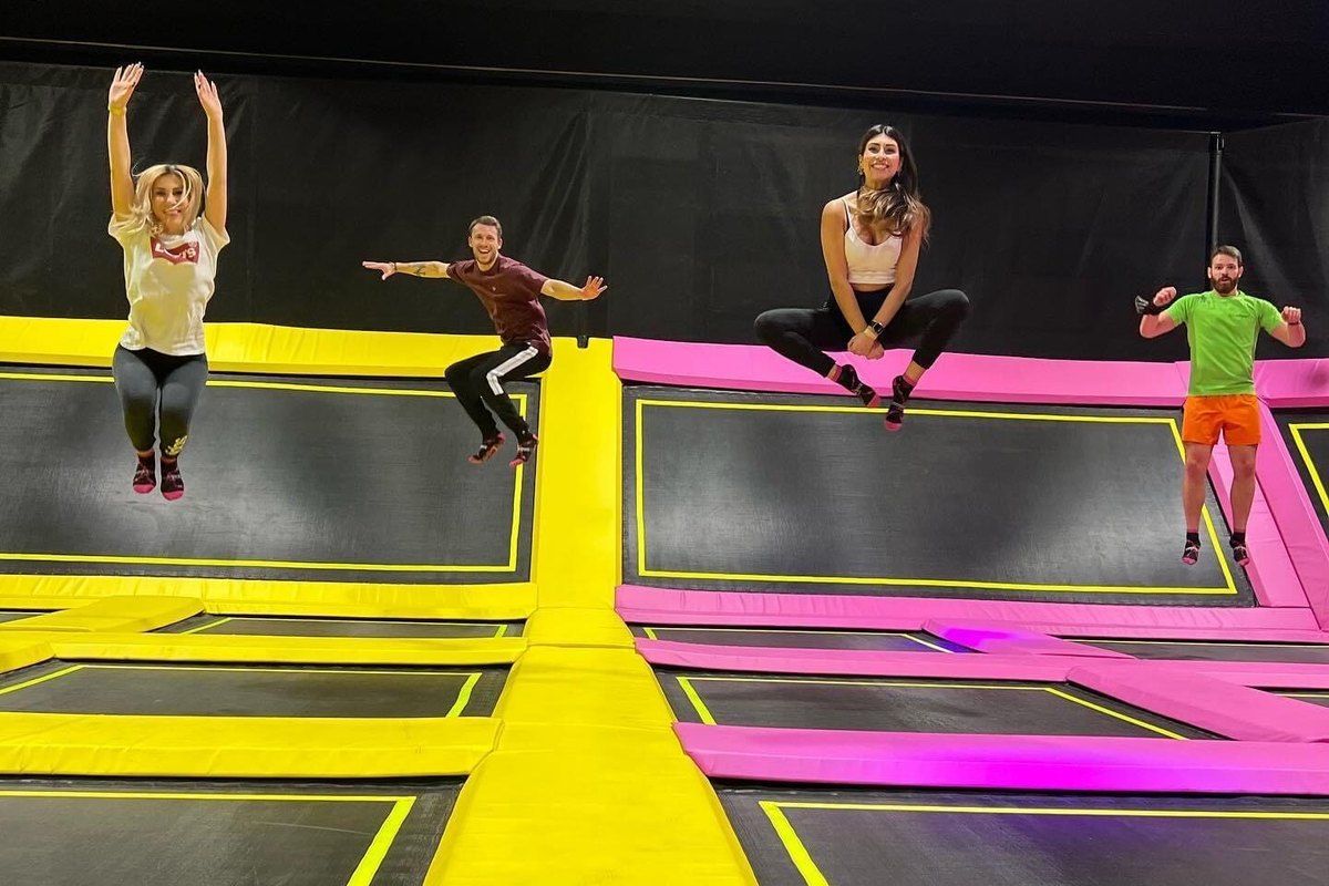 Jumpers mid-air over the pink and yellow trampoline grid at Hyperspace Milano