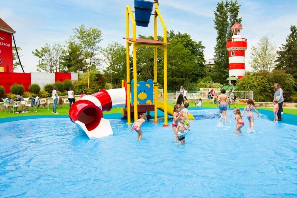 Children playing in a shallow splash pool with slides and a lighthouse at Leolandia