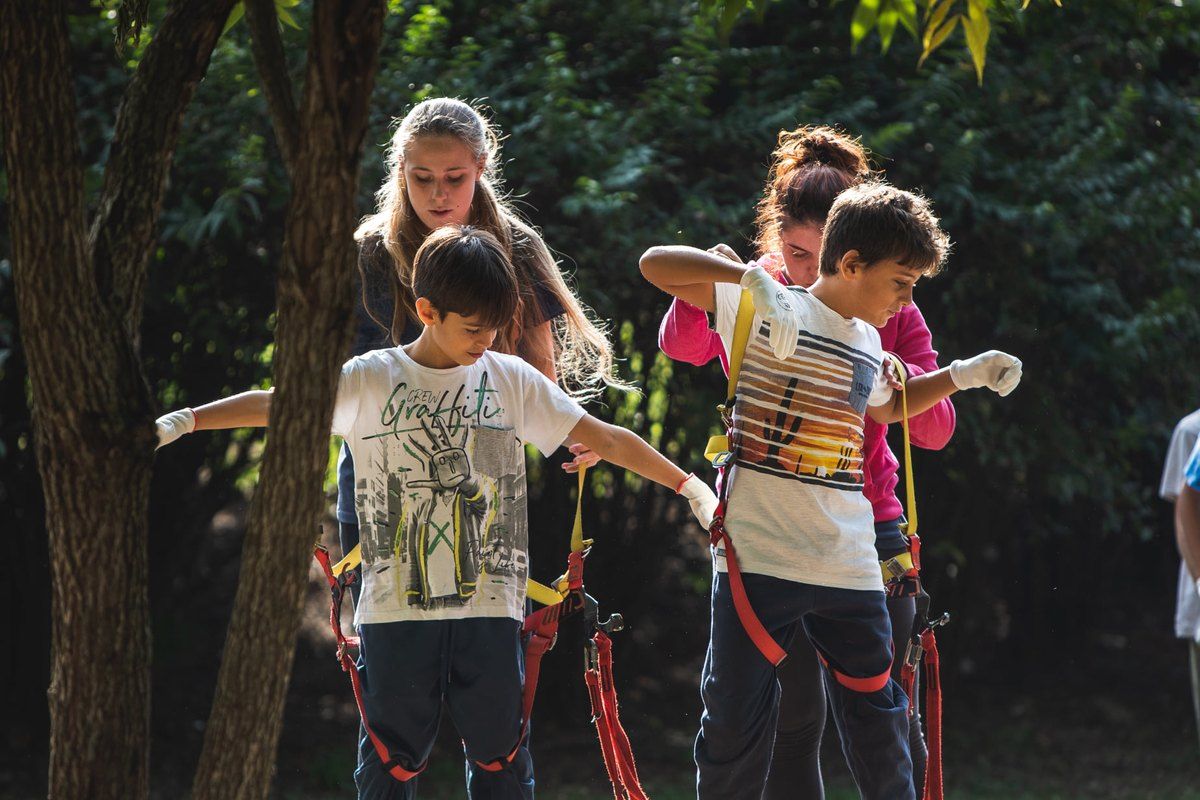 Children in climbing harnesses getting ready for the tree-top courses at Parco Avventura Milano in Parco Cassinis