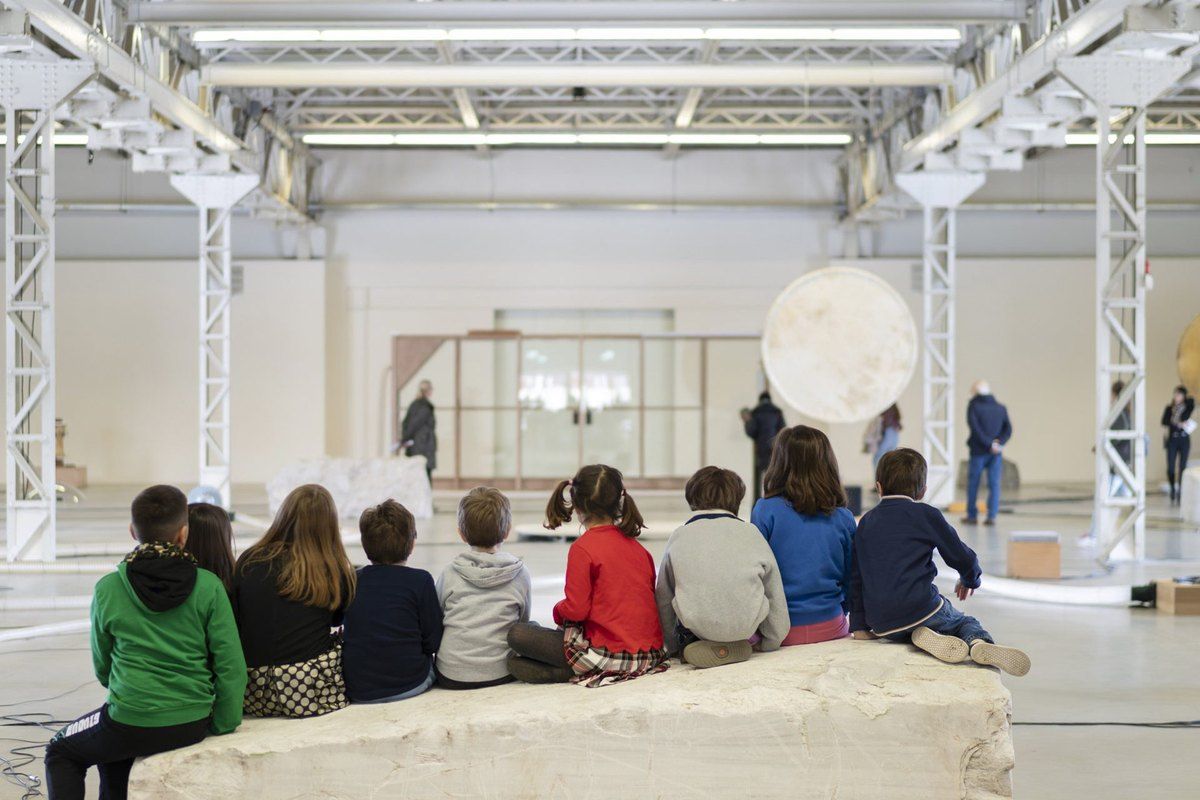 Children sitting together in the white exhibition hall during a Kids workshop at Pirelli HangarBicocca
