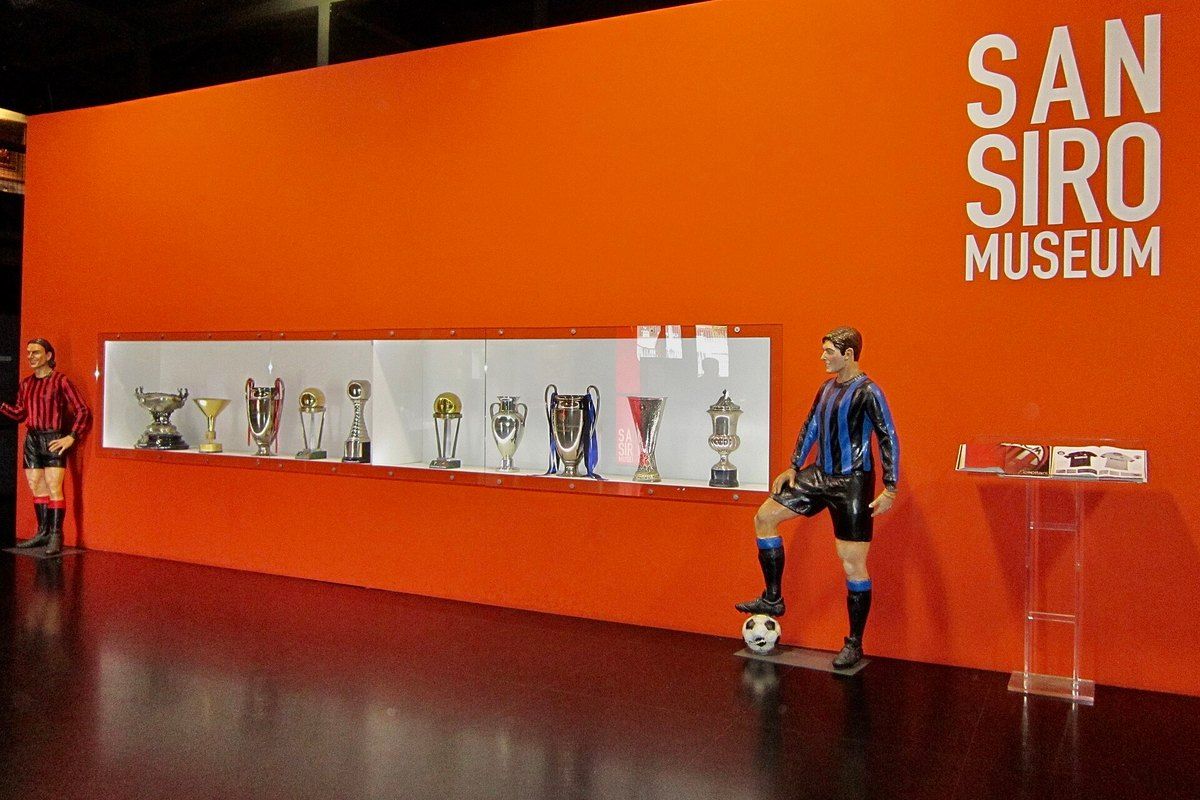 The trophy room of the San Siro Museum with life-size footballer figures against an orange wall