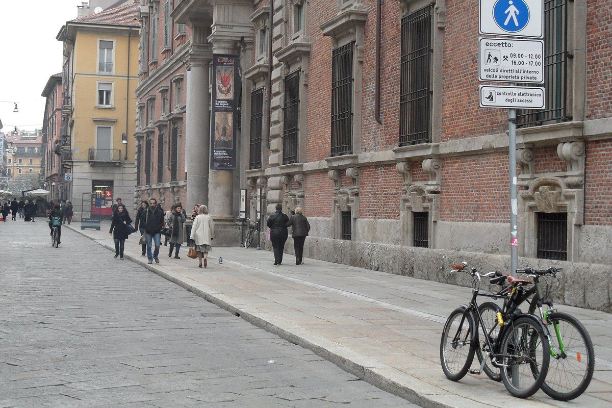 Pedestrians on the stone paving of Via Brera beside Palazzo Brera