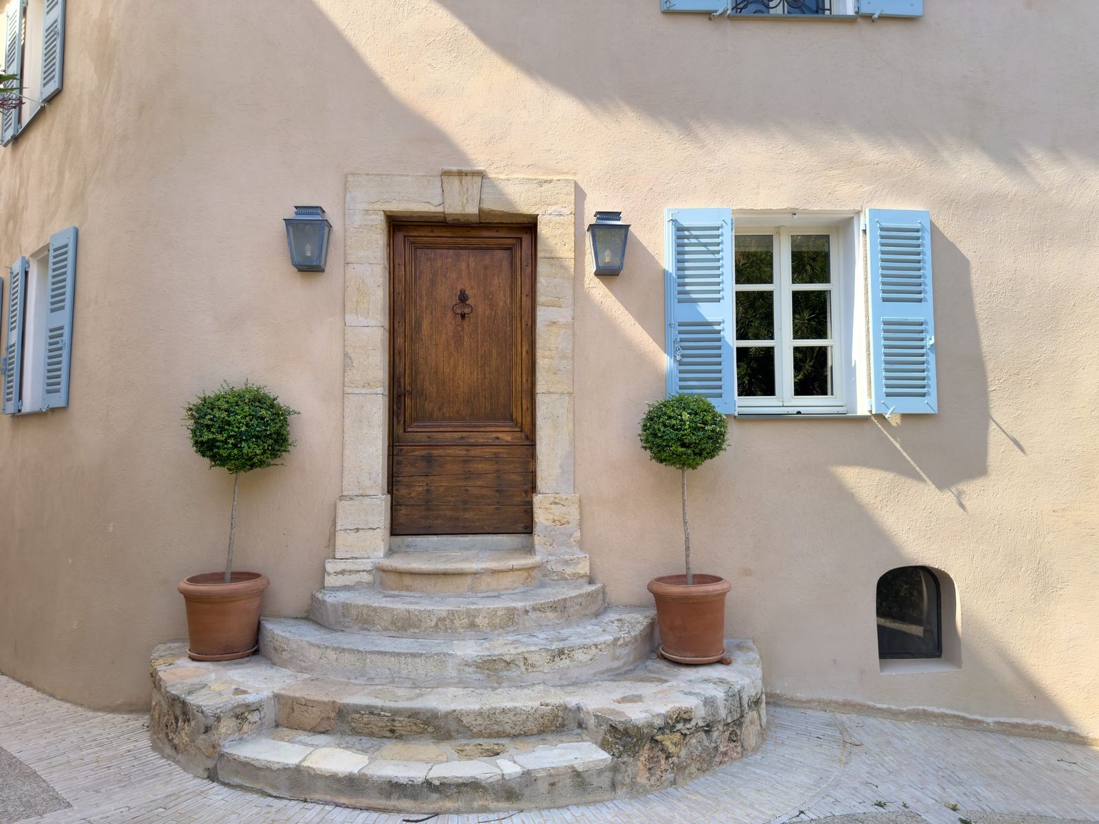 A house entrance with stone steps and blue shutters in Mougins