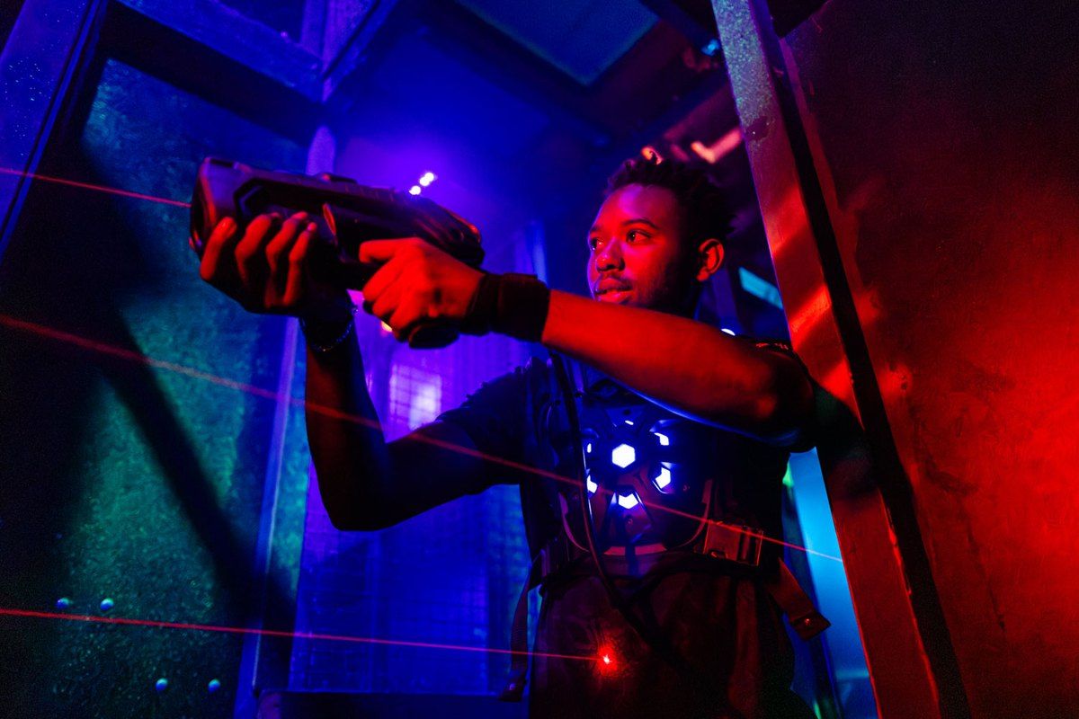 A player aiming a laser gun in the neon-lit maze at Laser Game Evolution Mougins