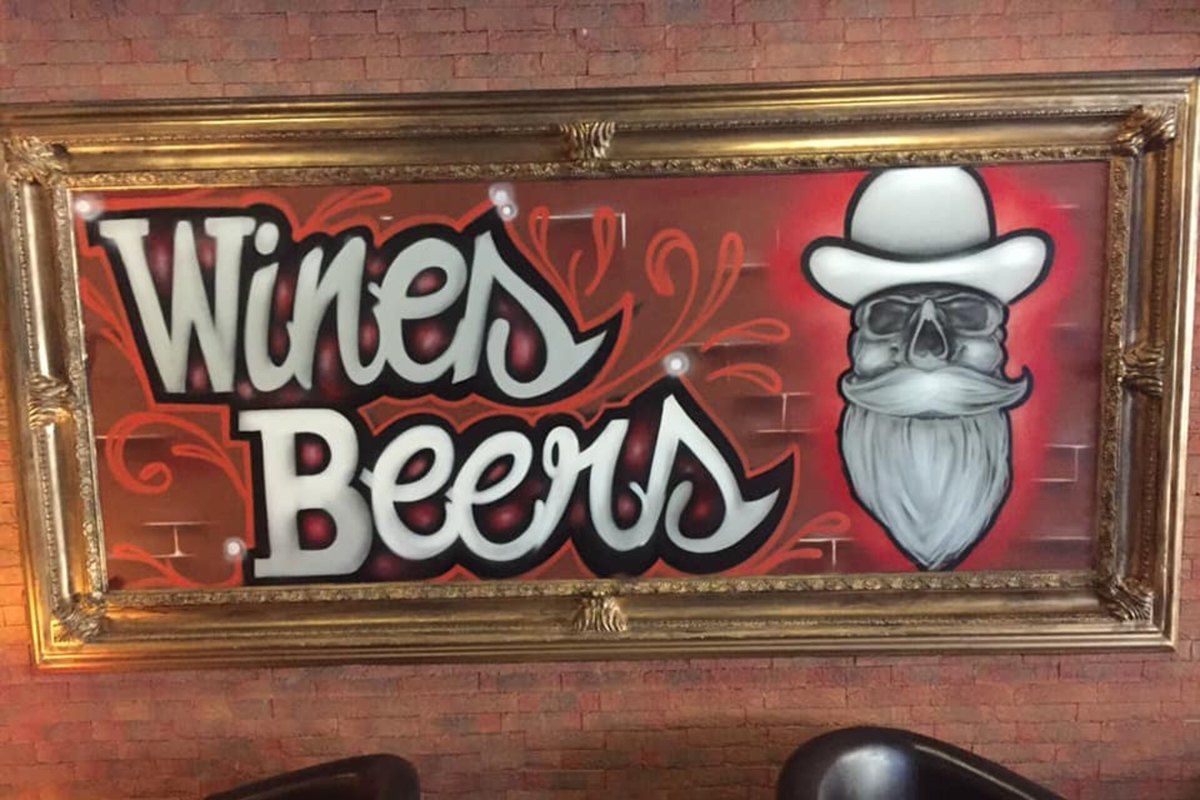 The painted Wines Beers sign above leather armchairs inside the bar in Mougins