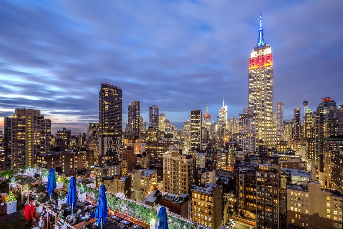 The Empire State Building lit at dusk above the 230 Fifth rooftop