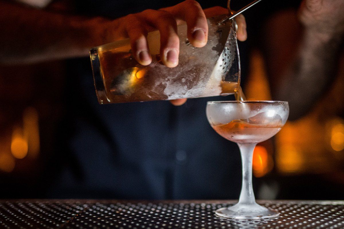 A bartender straining a cocktail into a coupe at Attaboy on the Lower East Side