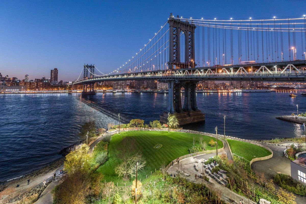Brooklyn Bridge Park at dusk, with the Manhattan Bridge and the lights of Manhattan across the East River