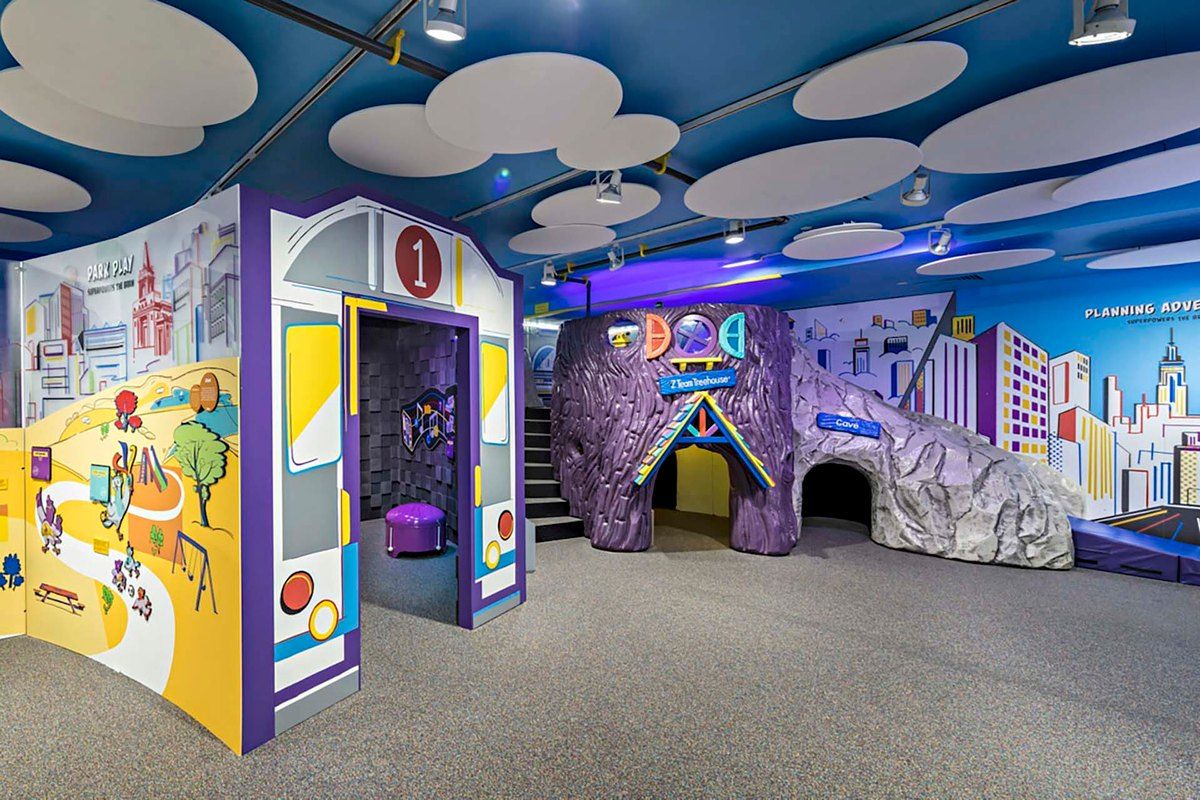 A colourful play area at the Children's Museum of Manhattan, with a bus-shaped entrance and a purple tunnel