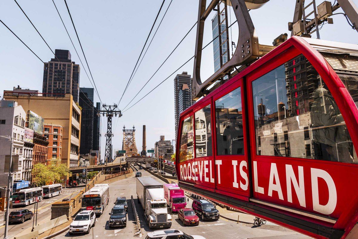 A red Roosevelt Island Tramway cabin above Second Avenue traffic