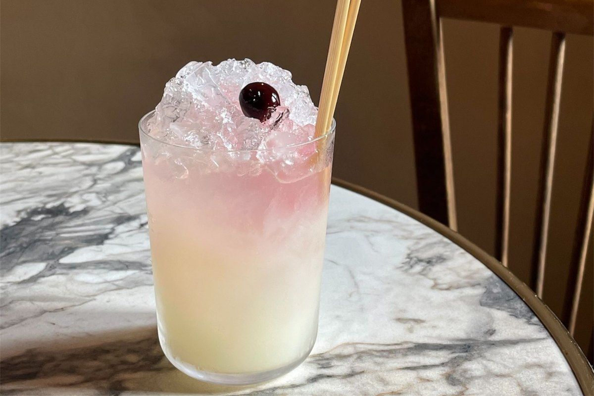 A pink crushed-ice cocktail topped with a cherry on a marble table at Povera, Nice