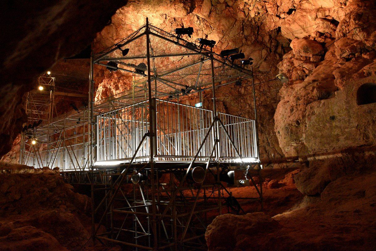 Inside the Grotte du Lazaret in Nice, with the lit walkway over the excavated cave floor