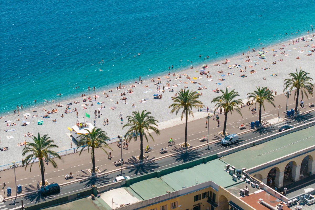 The pebble beaches of the Baie des Anges below the palm-lined Promenade des Anglais, seen from above