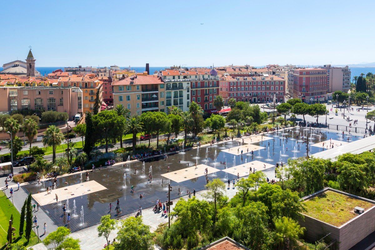 The water mirror and fountains of the Promenade du Paillon seen from above, with Nice's rooftops behind