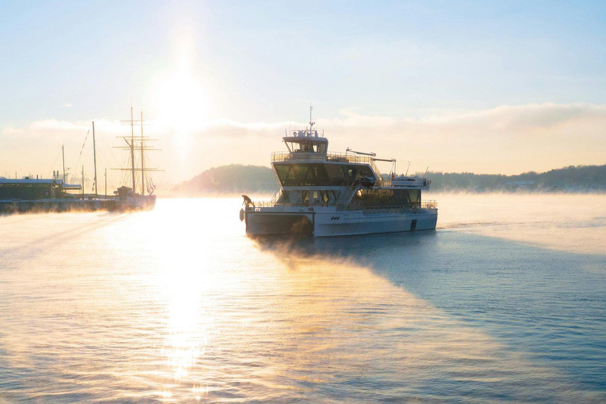 Brim Explorer's electric boat MS Brisen gliding through low winter sun and sea smoke on the Oslofjord