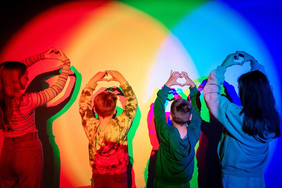 Children making heart shapes with their arms in red, green and blue coloured light in the science centre at the Norwegian Museum of Science and Technology
