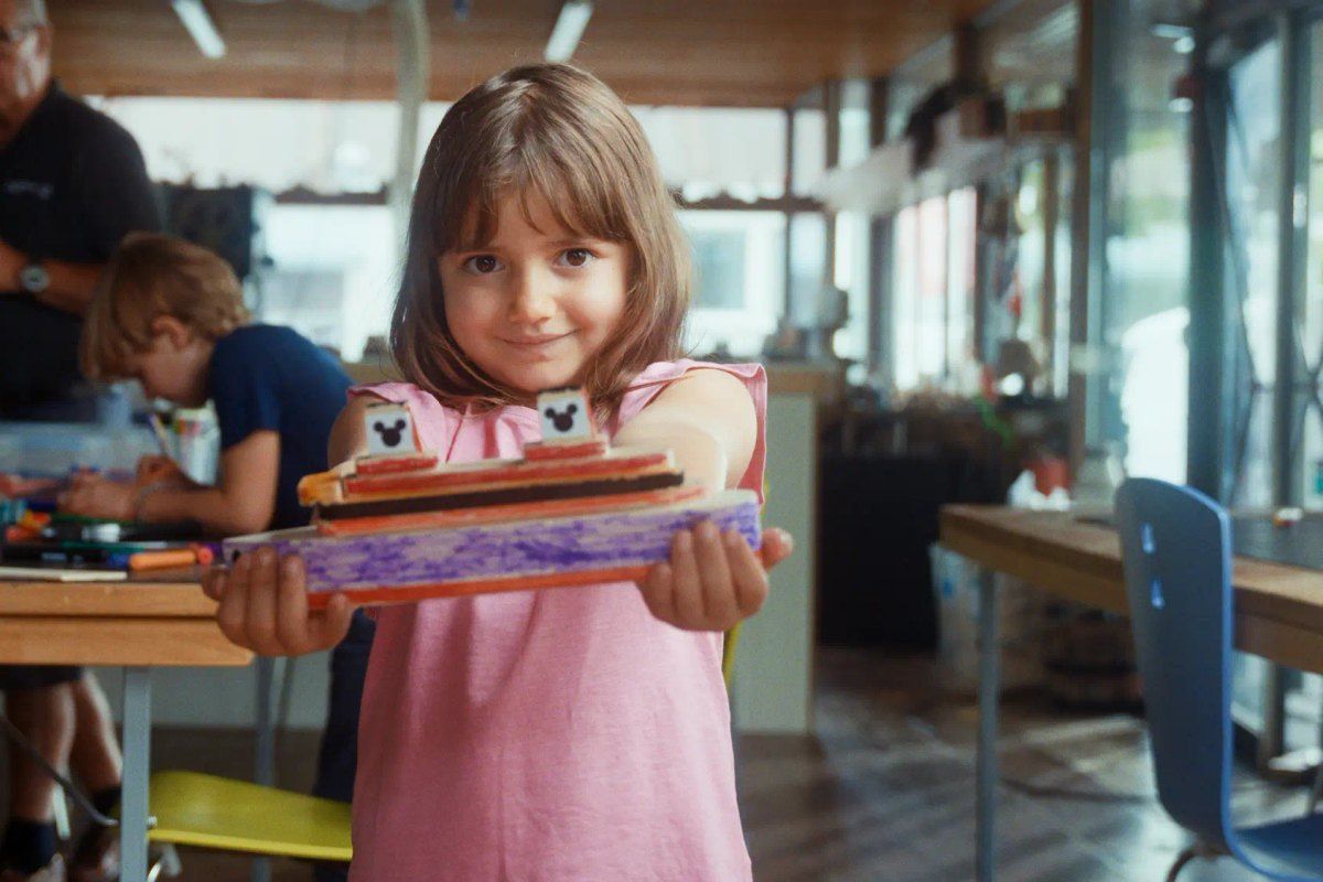 A girl holding up the wooden toy boat she has made in the children's boat workshop at the Norwegian Maritime Museum