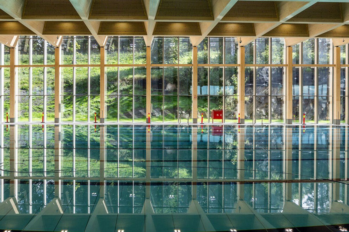 A pool hall at the new Tøyenbadet with tall windows looking out onto green trees