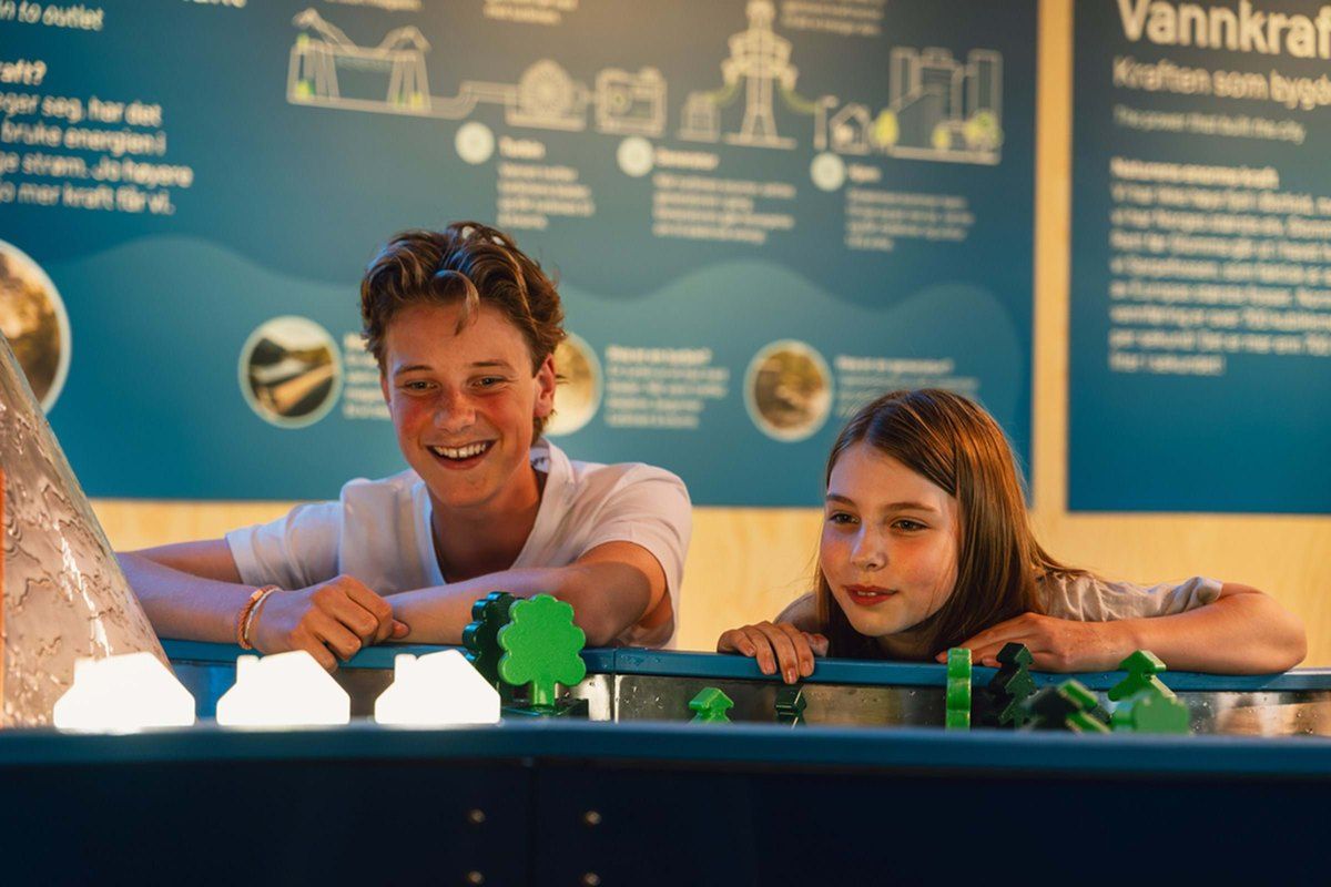 Two children laughing at a hands-on water-power exhibit at INSPIRIA science center