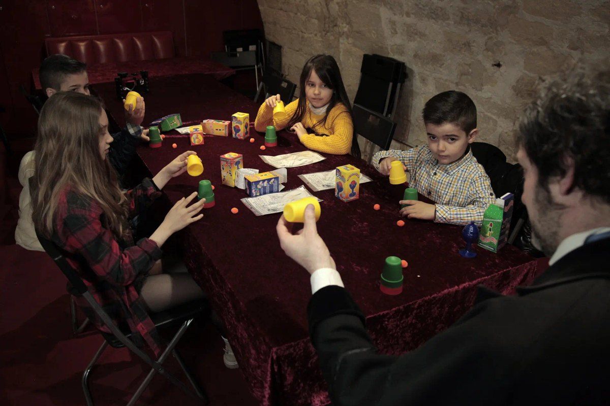 Children around a table of magic cups at the Musée de la Magie