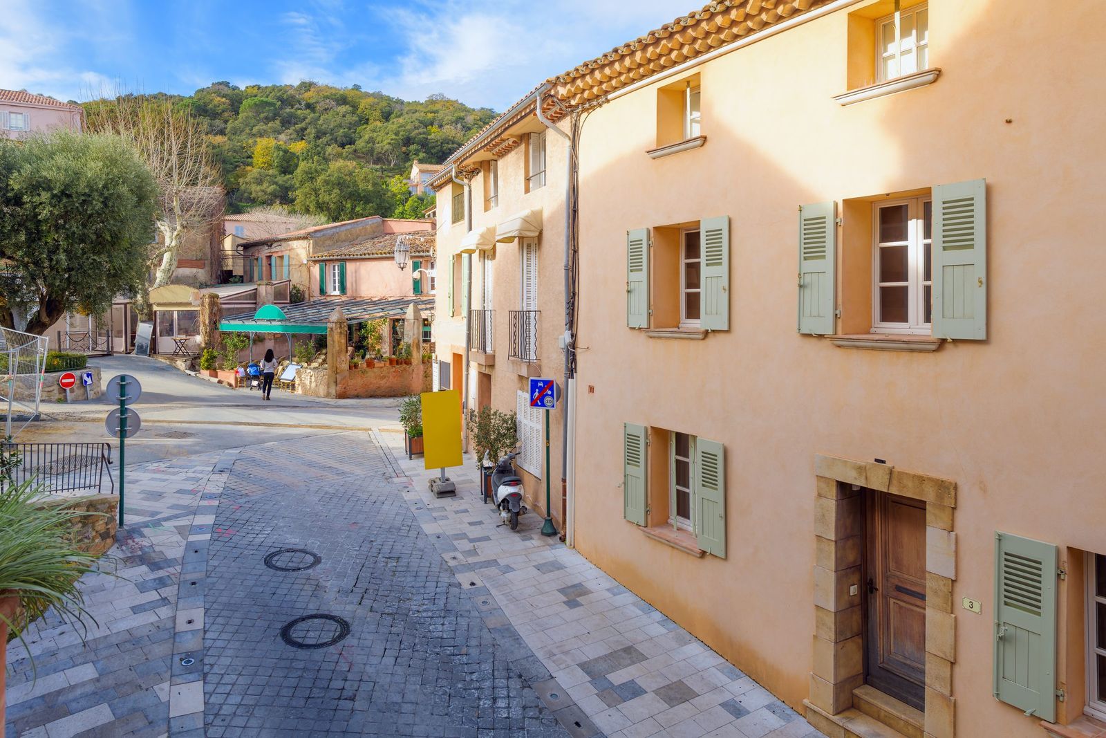 A cobbled street leading to a small square with café terraces in the centre of Ramatuelle