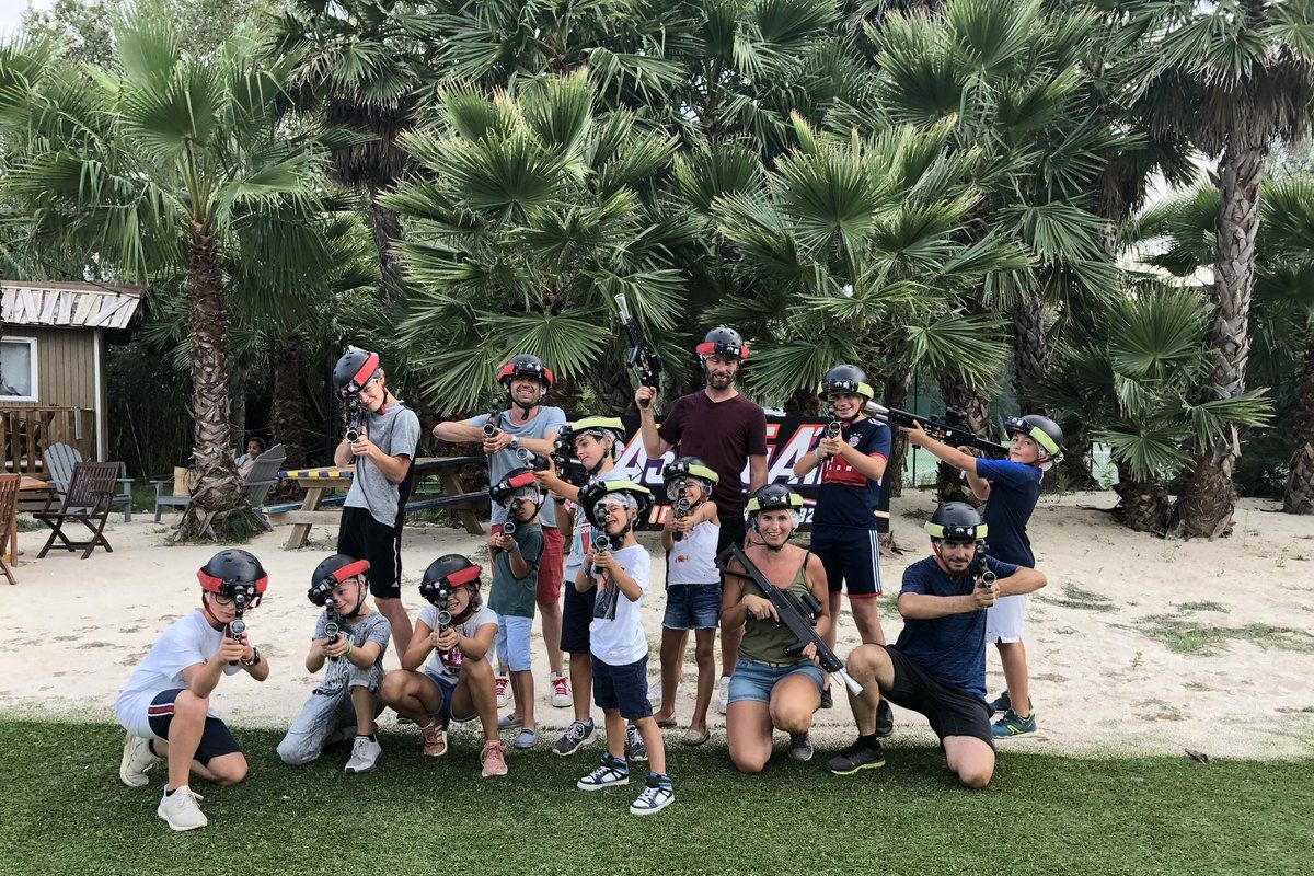 A group of children and adults with laser-game equipment among the palms at Laser Forest Game, Ramatuelle