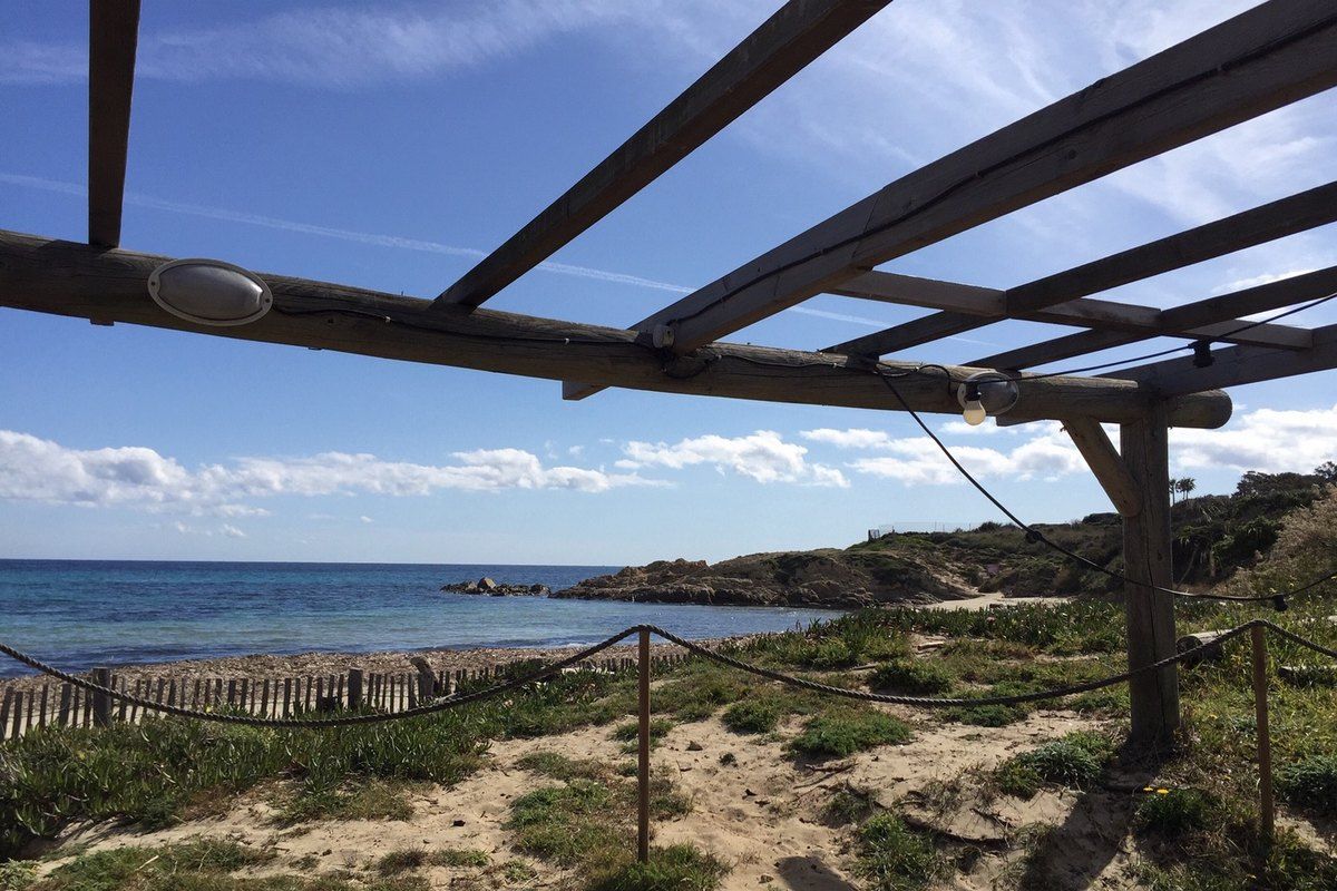 The pergola terrace of Le Migon looking over the dunes and the sea at the end of Pampelonne