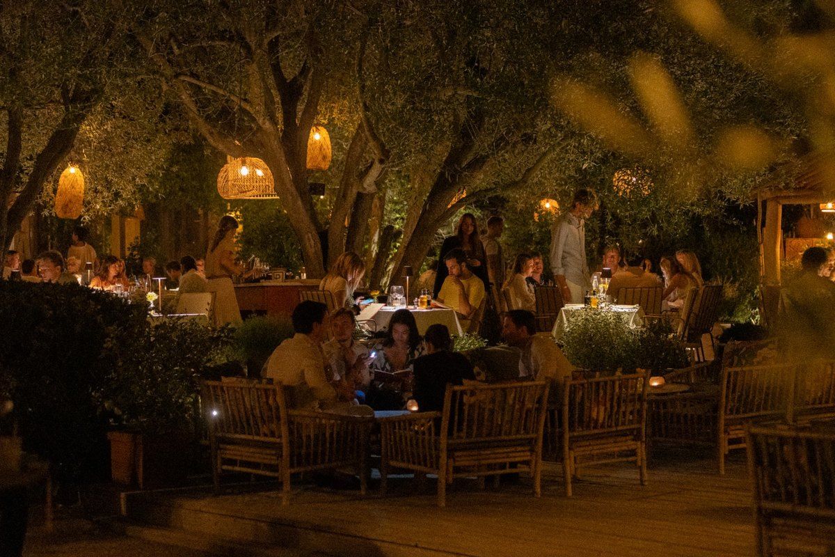 Tables lit by lanterns under the trees in the garden of Les Moulins de Ramatuelle at night