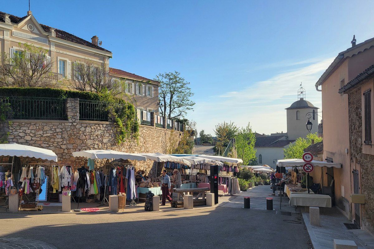 Market stalls under white awnings along a street of Ramatuelle village on market morning