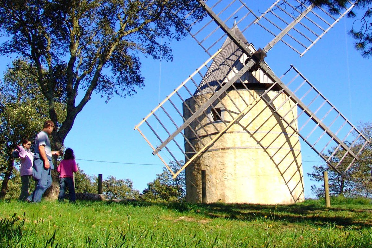 A family walking up to the Moulin de Paillas and its wooden sails above Ramatuelle