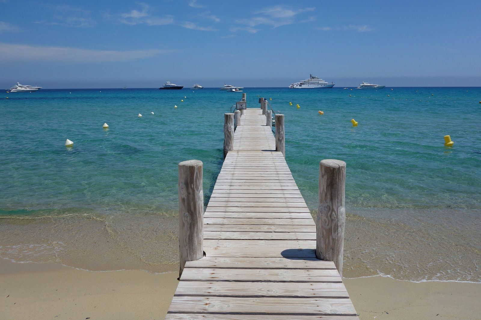 A wooden pontoon running out over the clear water of Pampelonne beach