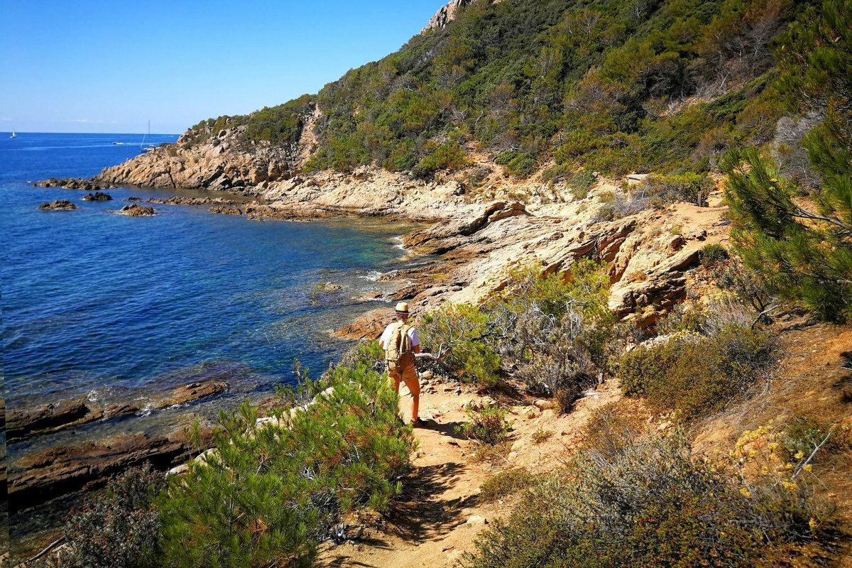 A walker on the rocky coastal path between Cap Camarat and L'Escalet above a clear blue sea