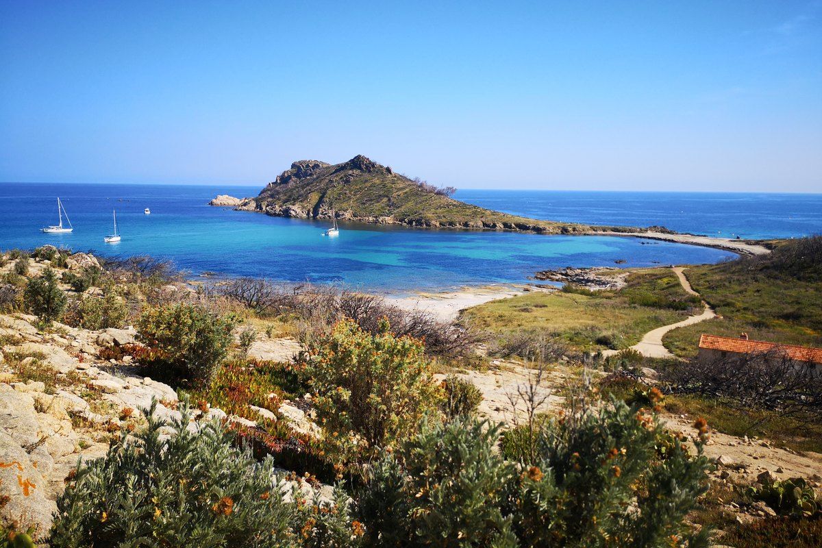 The sandy isthmus of Cap Taillat between two turquoise bays, seen from the coastal path
